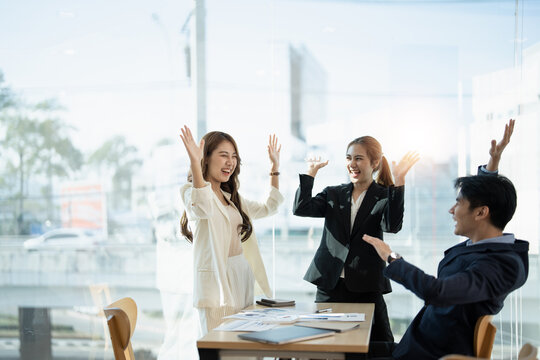 Young Multiethnic Diverse Creative Asian Group Huddle And High Five Hands Together In Office Workshop With Success Or Empower Expression In Teamwork. Young Asian Marketing Team With Copy Space