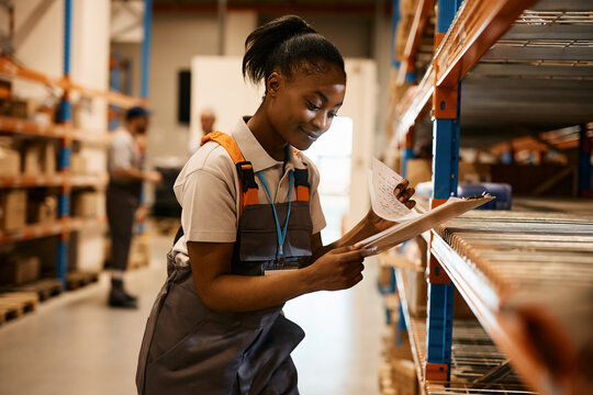 Young Black Woman Analyses Inventory List While Working At Distribution Warehouse.