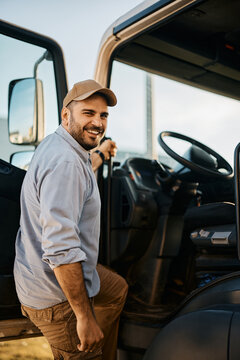 Happy truck driver entering in vehicle cabin and looking at camera.