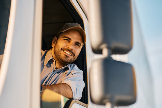 Happy Truck Driver Looking Through Side Window While Driving His Truck.