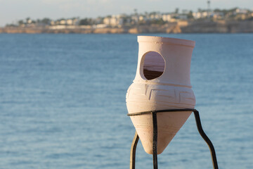 Fototapeta na wymiar Empty ceramic urn on the embankment. Garbage collection on the beach.
