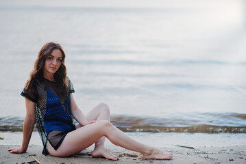 Fototapeta na wymiar Girl in a blue swimsuit on a summer sunny day on the beach