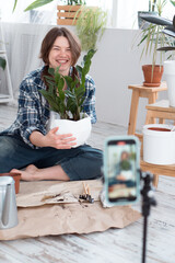 Woman making video how to repotting and watering plants using using smartphone at home