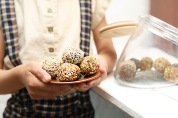 Cropped shot of child holding a plate with energy balls close up.