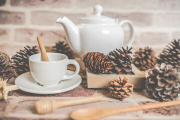 Tea concept, white teapot with white tea cup with dry leaves on wooden background.