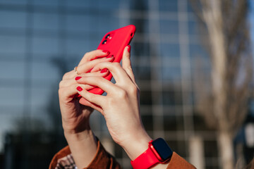 Woman taking photos using smartphone outdoors. Female hands wearing watch holding phone