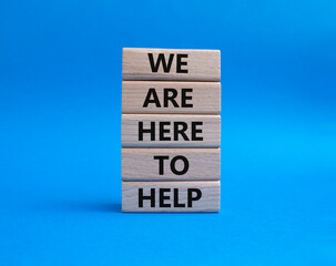 We are here to help symbol. Concept words we are here to help on wooden blocks. Beautiful blue background. Business and we are here to help concept. Copy space.
