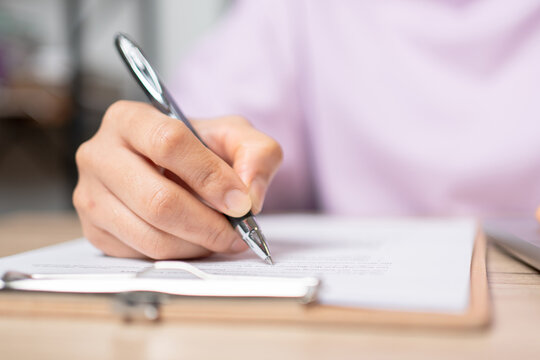 Close-up Hand of businesswoman writing signing documents on paper in office desk