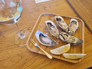 testing of oysters seafood, with glass of white wine on a wooden table, outside restaurant with a river view,  