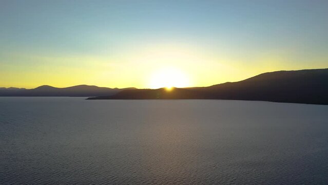 Sun Setting Behind Beautiful Mountain Peak Over Pristine Lake Tahoe in the Seara Nevado Mountains California - Aerial Drone View with Alpenglow