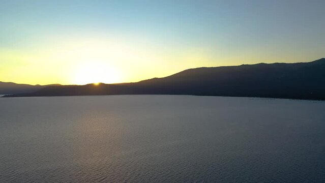 Sun Rising and Cresting Over Beautiful Mountain Peak at Scenic Lake Tahoe in the Seara Nevado Mountains California - Aerial Drone View with Alpenglow