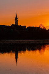 Obraz premium Beautiful sunset with reflections and a church silhouette near Pleinting, Danube, Bavaria, Germany