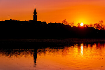 Fototapeta na wymiar Beautiful sunset with reflections and a church silhouette near Pleinting, Danube, Bavaria, Germany