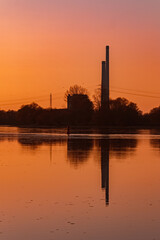 Obraz premium Beautiful sunset with reflections and a power plant silhouette near Pleinting, Danube, Bavaria, Germany