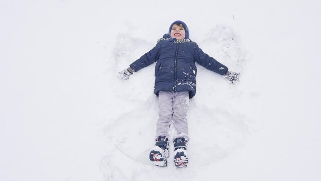 Happy boy making snow angel