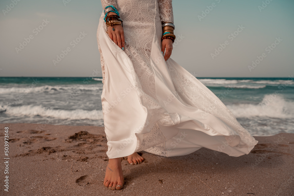 Wall mural model in boho style in a white long dress and silver jewelry on the beach. her hair is braided, and  - Wall murals