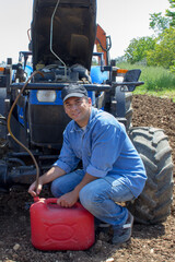 Photo of a farmer sucking diesel oil from a tractor tank with a rubber hose in the middle....
