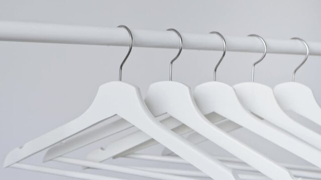 White empty wooden clothes hangers on white wall background. Concept of sale in the store, discounts, minimalistic advertising. Fashion, stylish metal hook hangers. Equipment for home, shop, boutique