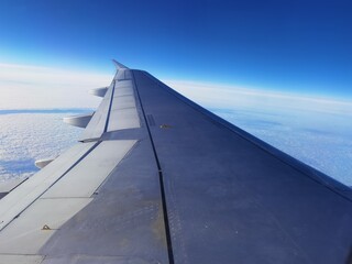 Fototapeta na wymiar Wing of a passenger airliner flying above the clouds in a blue sky