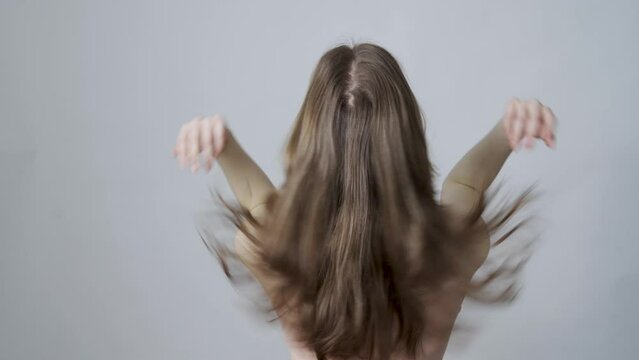 A young woman shaking her healthy hair. Back view
