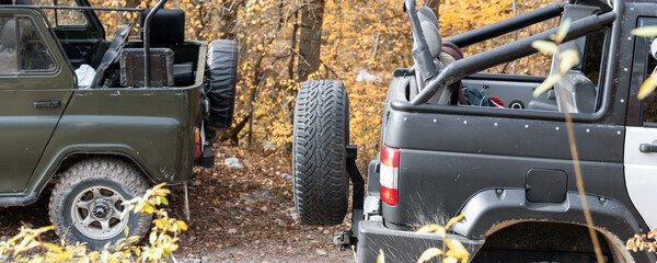 Pair of two 4x4 soviet suv covertible top vehicle on dirt gravel unpaved road in summer at sunset...