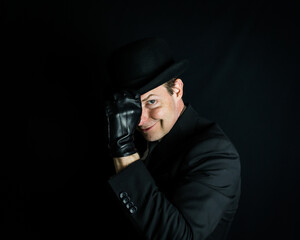 Portrait of British Businessman in Dark Suit and Leather Gloves Tipping Bowler Hat and Smirking....