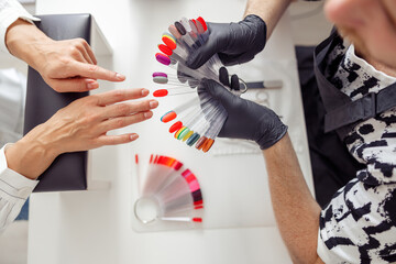 Manicure master helping to choose polish color in studio