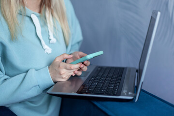 Closeup of female hands holding a mobile phone and surfing the internet while sitting on the couch at home.