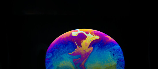 Half a soap bubble. Close-up. Black background. Bright colors. Side view. Imitation of an unknown planet. Science fiction