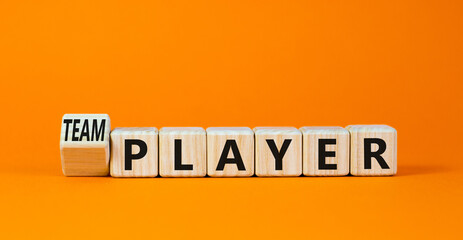 Player or teamplayer symbol. Turned wooden cubes and changed concept words Player to Teamplayer. Beautiful orange table orange background, copy space. Business player or teamplayer concept.