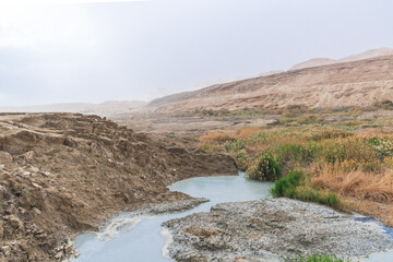 Sinkhole filled with turquoise water, near Dead Sea coastline. Hole formed when underground salt is dissolved by freshwater intrusion, due to continuing sea-level drop. . High quality photo