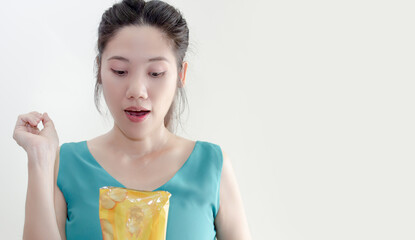 Asian beautiful woman are holding and looking to potato chip bag with happiness and loving to eat it.