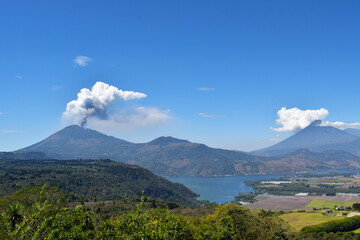 Panorámica del volcán Pacaya haciendo erupción al lado izquierdo, al lado derecho el volcán de agua y en la parte de abajo el lago de Amatitlán en Guatemala.