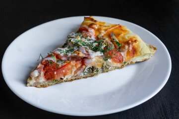 Slice of pizza on white plate on black table