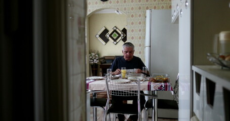 Lonely older man eating lunch alone in home kitchen