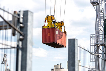 A container gantry crane on a rail loads the container into a barge standing on the banks of the river Rhine in Germany. - obrazy, fototapety, plakaty