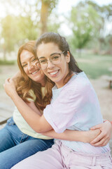 Naklejka premium Two happy girlfriends embracing looking at camera smiling