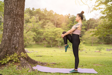 asian tattoo young woman doing yoga in the park
