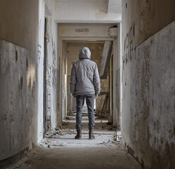 Man stands in an abandoned corridor. Rear view of man standing in corridor at abandoned building. 