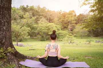 Fototapeta na wymiar asian tattoo young woman doing yoga in the park