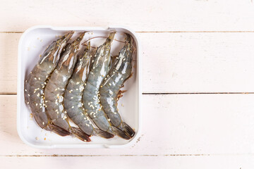 Fresh raw shrimps  top view in white plate, prinkle with white sesame on the table.