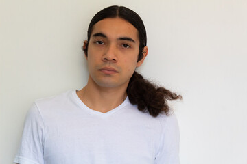 portrait of a non binary hispanic man with long hair on a white background