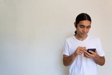 portrait of a non binary hispanic man with long hair on a white background using a cell phone