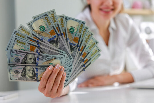 Smiling successful young businesswoman holding bunch of money