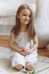 Cute adorable caucasian little girl at home with flowers. Smiling happy kid, childhood happiness concept 