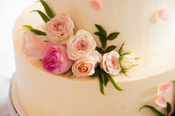white wedding cake decorated with mastic flowers on a white table. Picture for the menu or catalog of confectionery. wedding celebration concept