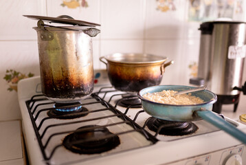 Some soaked oats are being cooked on the gas stove next to a hot water pot.