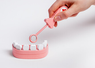 Hand checking teeth in jaw model with mouth mirror. Tooth checkup and treatment, oral hygiene concept. Children game at dentist. High quality photo