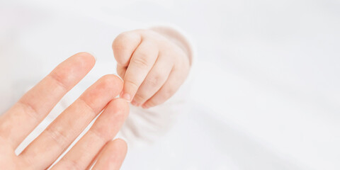 Naklejka premium Mother and baby hand web banner. newborn baby fingers, Close up. mothers Day. emotional bond between mother and child. copy space