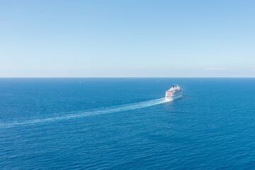 Cruise ship liner sails in the blue sea leaving a plume on the surface of the water seascape. Aerial view The concept of sea travel, cruises.